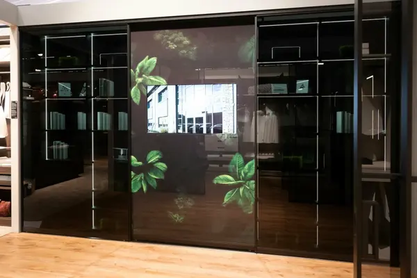 Moderne Glas-Schiebetür mit LED-Regalen, Pflanzenmotiven und integriertem Bildschirm.